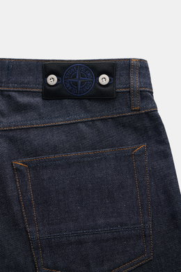 Close-up rear view of Stone Island Jeans 'Indigo Denim - Raw' navy showcasing pure cotton denim, textured quality, regular fit, straight cut, button fly, five-pocket style, and signature compass badge on waistband.