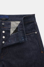 Stone Island Jeans 'Indigo Denim - Raw' navy shown from front close-up, featuring button fly, textured pure cotton denim, regular fit, straight cut, five-pocket style, and compass badge on waistband. Urban classic with untreated raw denim that adapts and 