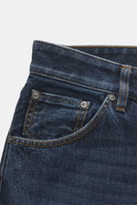 Nahaufnahme der PT Torino Denim Jeans 'Rebel Fit' dunkelblau, reine Baumwolle, leicht griffig, Button Fly, Five-Pocket-Stil, Leather Patch, Rebel Fit, reguläre Oberschenkelweite, knöchellang, von oben fotografiert.