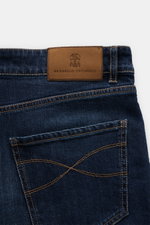 Close-up rear view of Brunello Cucinelli Jeans 'Leisure Fit' grey blue showing velour leather patch, cotton denim with stretch, five-pocket style, and logo stitching.