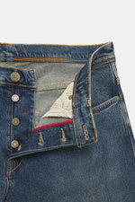 Close-up front view of Incotex Jeans smoky blue showing button fly, five-pocket style, leather patch, slim fit, slightly tapered design, elastic cotton denim with slightly grippy texture and authentic wash.