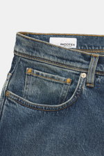 Close-up front view of Incotex Jeans smoky blue made of elastic cotton with slightly grippy texture, authentic wash, slim fit, slightly tapered, five-pocket style, button fly, and leather patch.