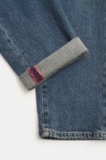 Close-up from above of Incotex Jeans smoky blue cuff showing denim made of elastic cotton with slightly grippy texture, authentic wash, slim fit, slightly tapered, five-pocket style, button fly, and leather patch.