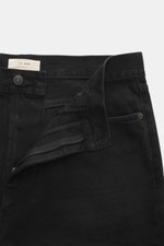 Close-up front view of The Row Jeans 'Vanya' black with open zip fly, black-textured pure cotton denim, five-pocket style, tapered fit.