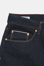 Nahaufnahme der Ace Denim Jeans 'AD 53' navy im Five-Pocket-Stil aus Selvedge-Denim mit leichterm Stretch, Button Fly, besticktem Patch, weichem Griff, sehr schmal zulaufendem Tapered Fit, fotografiert von vorne oben.