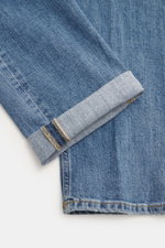 Close-up image from above of Dondup Jeans 'Bray' smoky blue showing folded cuff, denim made of elastic cotton, soft feel, authentic wash, regular fit, button fly, five-pocket style, and small metal initial.