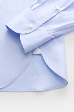 Close-up top view of Borrelli Business Shirt 'Nando' Shark Collar Light Blue cuff and sleeve, showcasing pure cotton fabric, fine weave, mother-of-pearl buttons, slim fit, classic sport cuff, and rounded hemline with hand-finished details.
