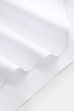 White fabric close-up showing fine weave and texture from a front angle, highlighting the Borrelli Business Shirt 'Nando' Shark Collar white’s pure cotton, soft touch, slim fit, French button placket, mother-of-pearl buttons, classic sport cuff, and round
