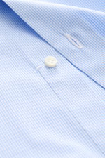 Borrelli Business shirt 'Nando' shark collar light blue/white checked shown close-up from above, highlighting fine check pattern, poplin cotton, mother-of-pearl button, and meticulous stitching. Masterful craftsmanship down to the smallest detail: The 'Na