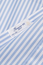 Close-up top-down view of the Finamore Business Shirt 'Sergio Napoli' Shark Collar Light Blue/White Striped label on smooth, high-quality striped poplin cotton fabric.

Additional description:  
<p>Stylish in the office: The 'Sergio Napoli' shirt by FINAM