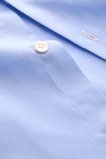 Nahaufnahme des Finamore Oxford-Hemds 'Sergio Napoli' Haifisch-Kragen hellblau mit feiner Oxford-Struktur, Knopf und Knopfloch, seitliche Perspektive.