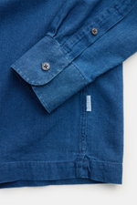 Close-up view of the cuff and hem of the 04651/ A trip in a bag Popover shirt 'Indigo' Kent collar dark blue, showing pure cotton twill fabric with mother-of-pearl buttons and a small woven side label.

<p>The popover shirt 'Indigo' by 04651/ A TRIP IN A 