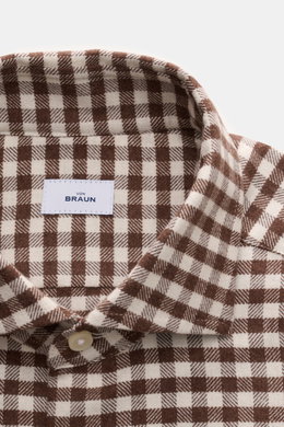 Nahaufnahme von BRAUN Hamburg Flanellhemd Haifisch-Kragen braun/offwhite kariert mit feinem Baumwoll-Strukturgewebe, weichem Griff, Slim Fit, französischer Knopfleiste und klassischer Sportmanschette, aus schräger Perspektive fotografiert.