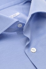 Nahaufnahme des Fray Piqué-Hemd Haifisch-Kragen 'Lione Cucitura' hellblau mit Haifischkragen, weißen Knöpfen und luftigem Baumwoll-Piqué, Slim Fit aus schräger Perspektive.