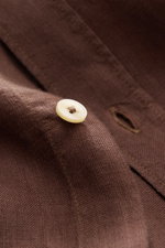 Close-up front view of von Braun Linen shirt shark collar brown showing a white button and fine brown linen texture, garment-dyed with typical fabric texture and soft feel. Effortlessly lightweight: This VON BRAUN shirt in pure linen has an airy feel and 