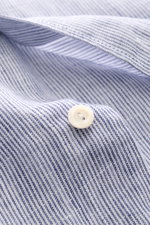 Close-up front view of von Braun Linen shirt shark collar navy/white striped showing fine striped pure linen fabric texture, white button, and airy, lightweight feel. Effortlessly lightweight: This VON BRAUN shirt in pure linen has an airy feel and a rela