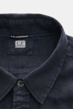 Close-up front view of the C.P. Company Linen shirt slim collar navy, showing the narrow collar, top button, and C.P. Company label inside. <section class="text-token-text-primary w-full focus:outline-none [--shadow-height:45px] has-data-writing-block:poi