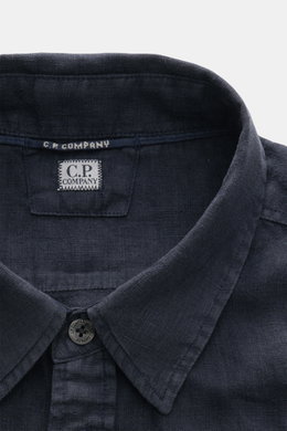 Close-up front view of the C.P. Company Linen shirt slim collar navy, showing the narrow collar, top button, and C.P. Company label inside. <section class="text-token-text-primary w-full focus:outline-none [--shadow-height:45px] has-data-writing-block:poi