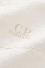 C.P. Company Linen shirt slim collar off-white shown in close-up from above, highlighting pure linen fabric, soft feel, garment-dyed texture, and subtle logo print on pocket section. <section class="text-token-text-primary w-full focus:outline-none [--sha