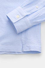 Nahaufnahme des Giampaolo Seersucker Popover-Hemd Haifisch-Kragen hellblau/weiß gestreift, Detail von Manschette, Knopfleiste und Saum aus leicht elastischem Baumwoll-Seersucker.