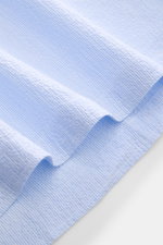 Giampaolo Seersucker Popover-Hemd Haifisch-Kragen hellblau/weiß gestreift, Detailaufnahme des leichten, elastischen Baumwollstoffs mit Quetschfalte und geradem Saum.