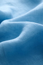 Close-up image of light blue linen fabric showing texture and weave, photographed from a side angle. MC2 Saint Barth Leinenhemd 'Pamplona' Haifisch-Kragen rauchblau offers a perfect casual summer look with linen canvas weave, soft touch, slim fit, shark c