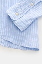 Close-up of Polo Ralph Lauren Linen shirt button-down collar light blue/white striped showing cuff and rounded hem from a top-down angle.

<p>A summer classic from POLO RALPH LAUREN: This minimalist slim fit shirt in the finest linen with button-down coll