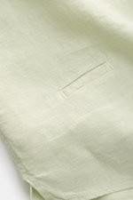 Close-up detail of the small welt pocket and hem vents of the 04651/ A trip in a bag Linen shirt 'Linen Guru' grandad collar pastel green, photographed from above. Summer for your skin: The airy casual shirt 'Linen Guru' by 04651/ A TRIP IN A BAG is made 