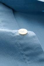 Alt tag (125 characters max): Close-up front view of button on smoky blue 04651/ A trip in a bag Casual shirt 'Cloudy Shirt' slim collar fabric.

Description:
<p><span class="_fadeIn_m1hgl_8">Lightweight and comfortable for hot days: The casual shirt 'Clo