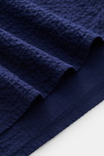 Close-up view of navy seersucker fabric texture and hem of the 04651/ A trip in a bag Seersucker shirt Kent collar navy, made of pure cotton.

Description: <p><span class="_fadeIn_m1hgl_8">Effortlessly </span><span class="_fadeIn_m1hgl_8">casual</span><sp