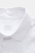 Close-up front view of the 04651/ A trip in a bag Seersucker shirt Kent collar white, showing textured seersucker cotton fabric and label.

<p><span class="_fadeIn_m1hgl_8">Effortlessly </span><span class="_fadeIn_m1hgl_8">casual</span><span class="_fadeI