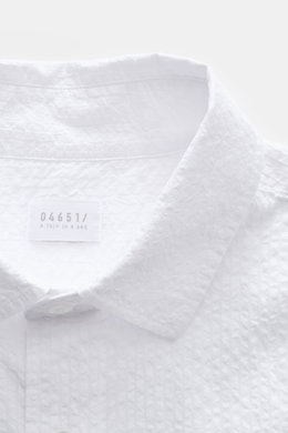 Close-up front view of the 04651/ A trip in a bag Seersucker shirt Kent collar white, showing textured seersucker cotton fabric and label.

<p><span class="_fadeIn_m1hgl_8">Effortlessly </span><span class="_fadeIn_m1hgl_8">casual</span><span class="_fadeI