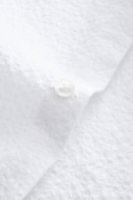 Close-up view of the white seersucker fabric and button on the cuff of the 04651/ A trip in a bag Seersucker shirt Kent collar white.

<p><span class="_fadeIn_m1hgl_8">Effortlessly </span><span class="_fadeIn_m1hgl_8">casual</span><span class="_fadeIn_m1h