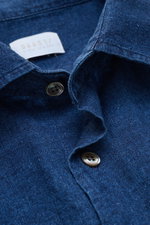 Close-up image of the collar and button placket of the 04651/ A trip in a bag Casual shirt 'Indigo Shirt' slim collar navy, showing navy blue linen-cotton fabric with textured weave and translucent buttons. The product is photographed from a top-front ang