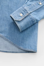 Nahaufnahme des Ärmelaufschlags und Saumverlaufs vom Thom Browne Jeanshemd Button-Down-Kragen rauchblau aus reiner Baumwolle, Regular Fit, mit leichter Griffigkeit, Streifen-Print am Ärmel, klassischer Sportmanschette und aufgesetzter Knopfleiste, fotogra