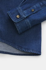 Nahaufnahme des Ärmels mit klassischer Sportmanschette und gerundetem Saumverlauf des A.P.C. Jeanshemds „Greg“ navy, reine Baumwolle, weicher Griff, Oversized, Button-Down-Kragen, aufgesetzte Brusttasche, französische Knopfleiste, dezentes Logo-Stitching.