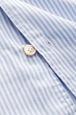 Nahaufnahme des Borrelli Oxford-Hemd 'Ettore' Haifisch-Kragen hellblau/weiß gestreift von schräg oben, reine Baumwolle, weicher Griff, Slim Fit, handgenäht, französische Knopfleiste mit Perlmuttknöpfen.