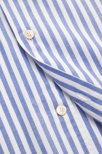Close-up, angled top view of Borrelli Oxford shirt 'Ettore' shark collar blue/white striped, showing pure cotton fabric, soft touch, slim fit, hand-sewn details, French placket with mother-of-pearl buttons, classic sport cuff, back waist darts, and rounde