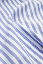 Close-up angled view of the fabric of Borrelli Oxford shirt 'Ettore' shark collar blue/white striped, showing pure cotton, soft touch, slim fit, hand-sewn texture with shark collar, French placket with mother-of-pearl buttons, classic sport cuff, back wai