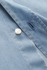 Nahaufnahme aus seitlicher Perspektive des Borrelli Jeanshemd Haifisch-Kragen rauchblau mit Knopf, Denim aus reiner Baumwolle, weicher, leichter Qualität, handgefertigt, Slim Fit, Haifisch-Kragen, aufgesetzte Knopfleiste, klassische Sportmanschette und ge