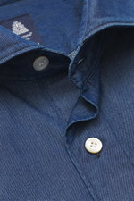 Close-up top-down view of the Finamore Chambray shirt 'Sergio Gaeta' shark collar dark blue, showing pure cotton chambray fabric with very soft feel, slim fit, shark collar, French button placket with mother-of-pearl buttons, classic barrel cuffs, extra-l