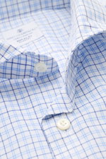 Close-up front-angle view of the Giampaolo Casual-Hemd Haifisch-Kragen blau/weiß kariert showing soft cotton fabric, blue/white check pattern, shark collar, white buttons, and label.

Description: <p>Ein echter Allrounder vom Hemdenexperten GIAMPAOLO: M