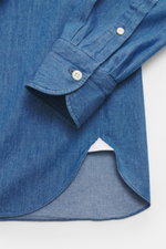 Nahaufnahme des Ärmel- und Saumbereichs vom Giampaolo Chambray-Hemd Haifisch-Kragen blau aus reiner Baumwolle mit softer Haptik, klassischer Sportmanschette, französischer Knopfleiste und gerundetem Saum, fotografiert von oben.