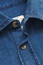 Nahaufnahme des Jacob Cohen Jeanshemds schmaler Kragen blau, von oben fotografiert, zeigt weichen Denim aus reiner Baumwolle, Kent-Kragen, Knopfleiste und dezentes Logo-Stitching.