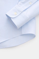 A close-up front view of the Ami Paris Casual Shirt Button-Down Collar Light Blue/White Striped cuff and hem, showing pure cotton fabric in a classic stripe design with patch button placket, soft touch, oversized fit, classic sport cuff, and slightly roun