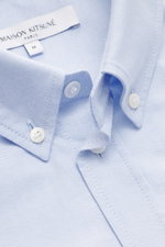 Maison Kitsuné Oxford shirt button-down collar light blue shown close-up from above, highlighting pure cotton Oxford fabric, soft feel, regular fit, button-down collar, signature logo stitching, classic barrel cuffs, inverted pleat on the back, and rounde
