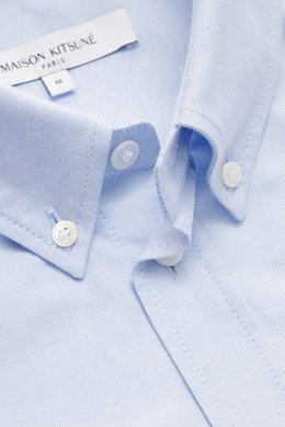 Maison Kitsuné Oxford shirt button-down collar light blue shown close-up from above, highlighting pure cotton Oxford fabric, soft feel, regular fit, button-down collar, signature logo stitching, classic barrel cuffs, inverted pleat on the back, and rounde