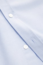 Maison Kitsuné Oxford shirt button-down collar light blue shown in close-up from above, featuring pure cotton Oxford fabric, soft feel, regular fit, button-down collar, signature logo stitching, classic barrel cuffs, inverted pleat on the back, and rounde