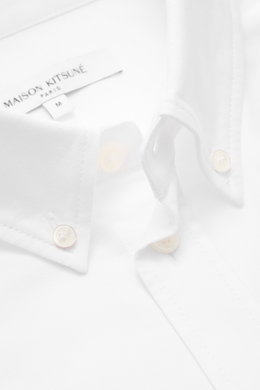 Maison Kitsuné Oxford shirt button-down collar white shown close-up from front angle, features pure cotton Oxford fabric, soft feel, regular fit, button-down collar, signature logo stitching, classic barrel cuffs, inverted pleat on back, and rounded hem.