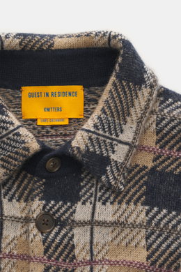 Close-up front view of the Guest In Residence Cashmere knit shirt light brown/beige/navy checkered, showing pure cashmere material, soft feel, medium-fine knit pattern, regular fit, smooth button placket, turn-down collar, breast pockets with flap and but